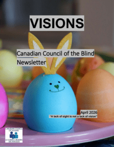 Closeup of a smiling blue Easter egg with a green heart-shaped nose and mouth, and brown and white bunny ears attached to the top. In the blurred background are several other colourful Easter eggs. They all sit above a pink plate.