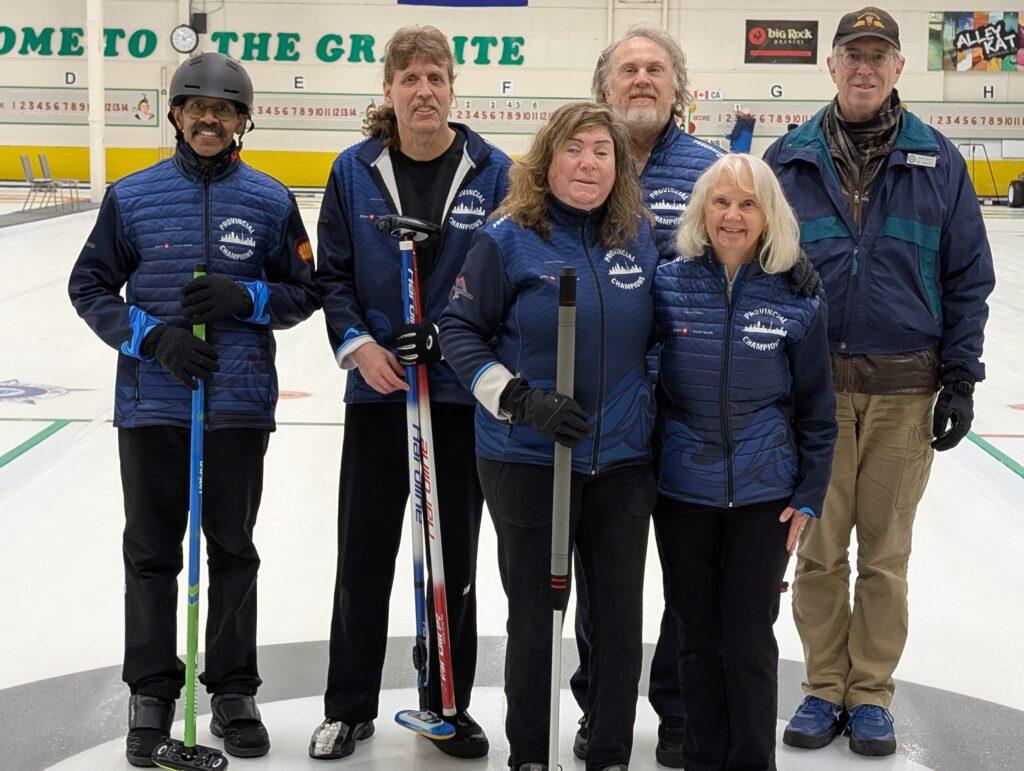 Team Ontario players stand on the ice wearing their navy blue team jackets, each smiling for the camera. Three players on the left are holding brooms.