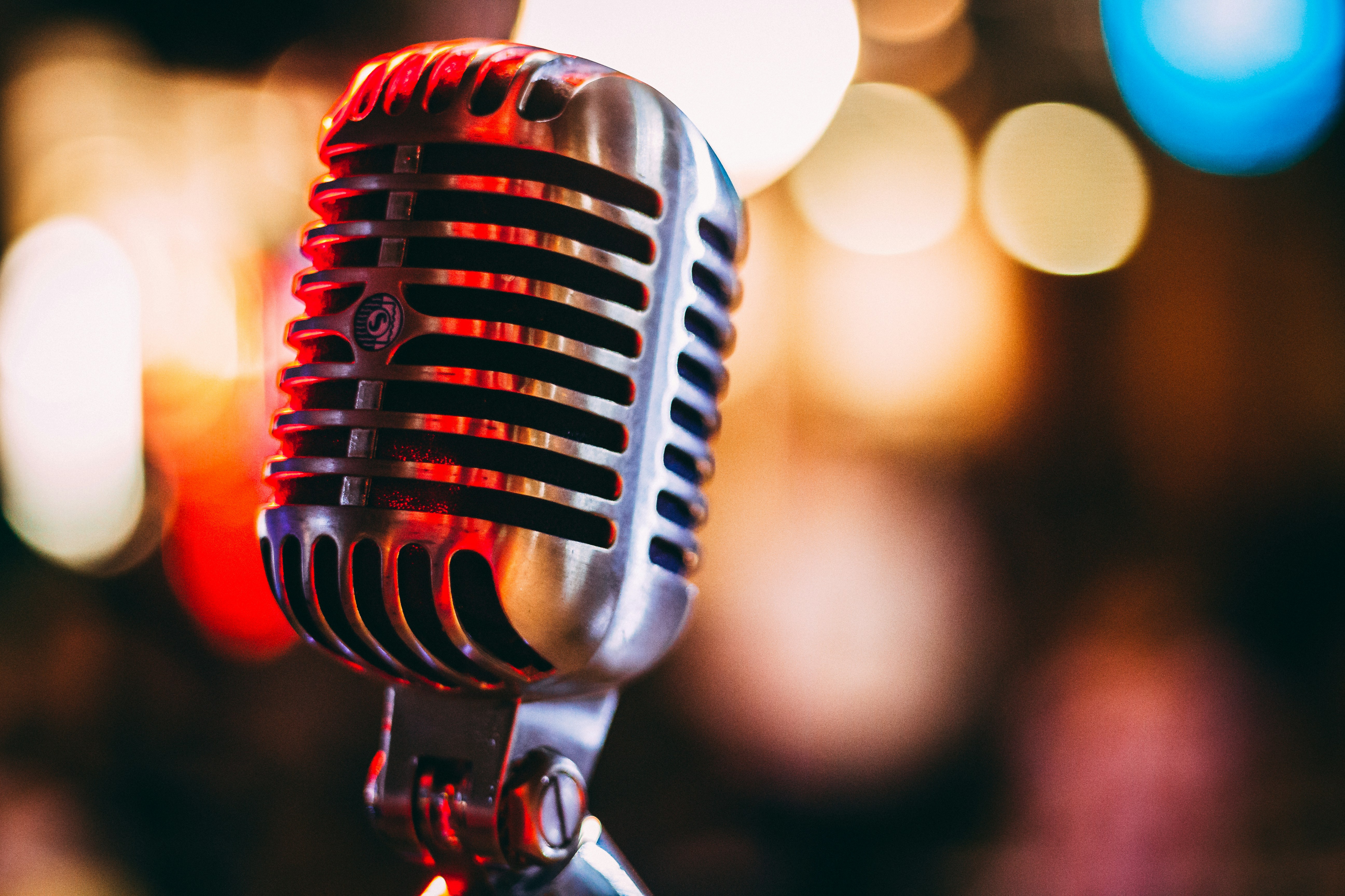 Close-up of a vintage silver microphone with lights in the blurred background.