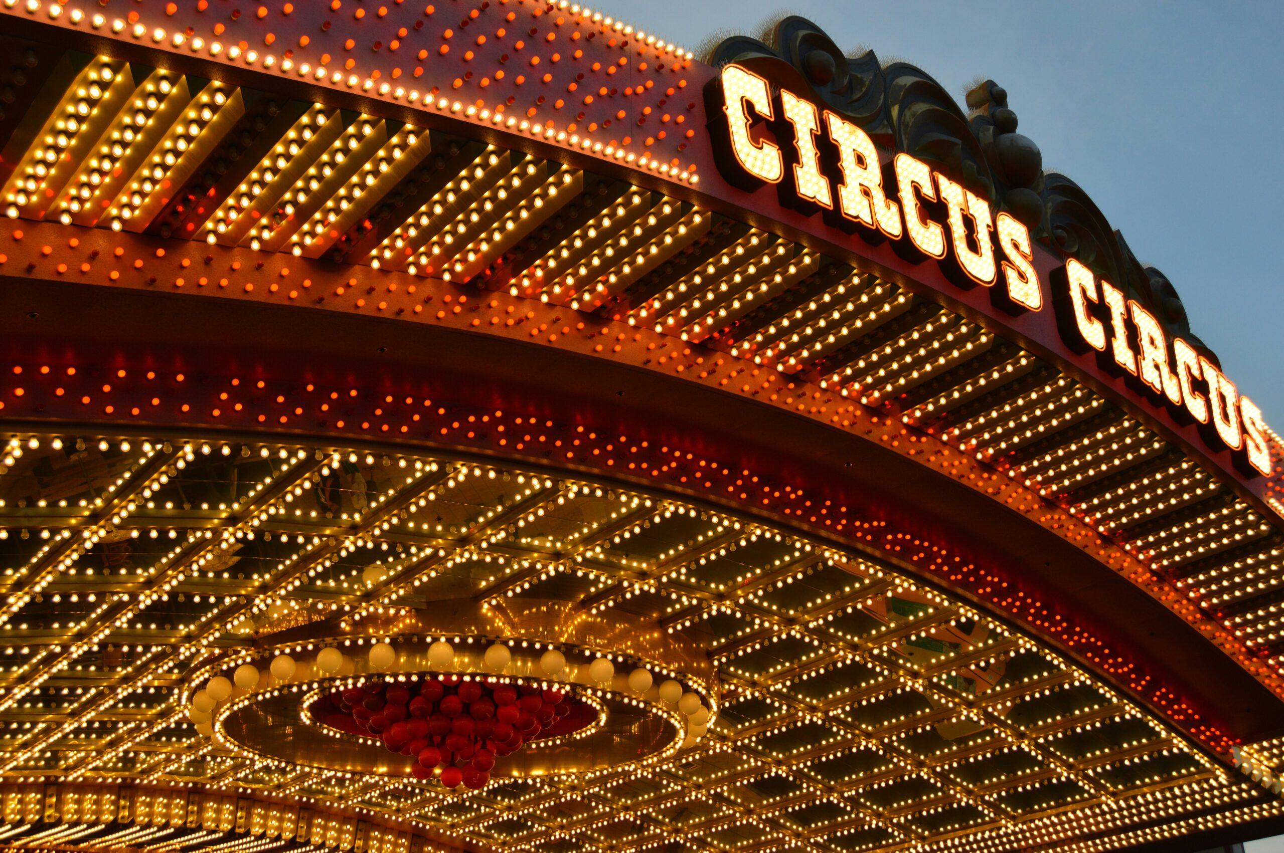 The ceiling of a well-lit circus in red and yellow with the text “Circus Circus” above. Red and gold balloons can be seen in a circular shape on the ceiling inside.