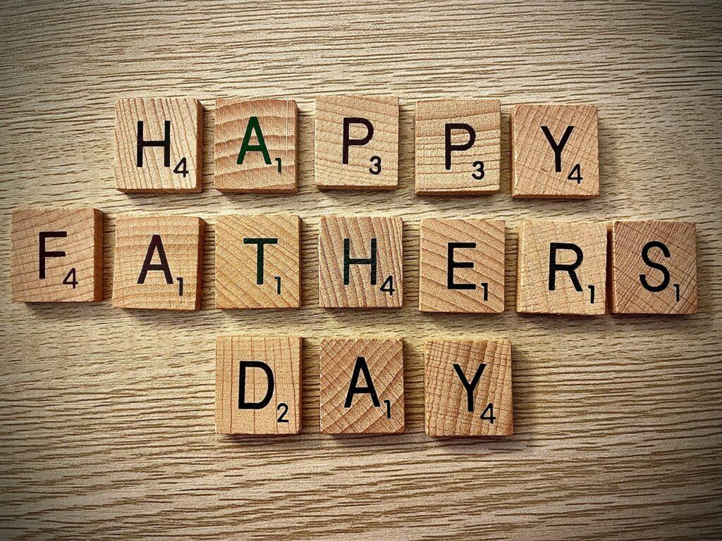 Wooden scrabble pieces read “Happy Father’s Day” against a wooden table.