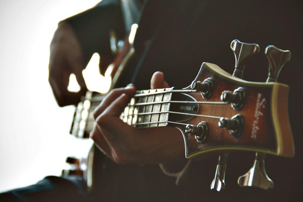 Close-up of a person sitting and playing a wooden guitar against a bright white background.
